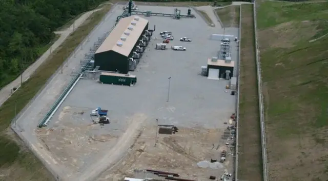 Aerial of a graded gravel compound with a long building and a fenced edge