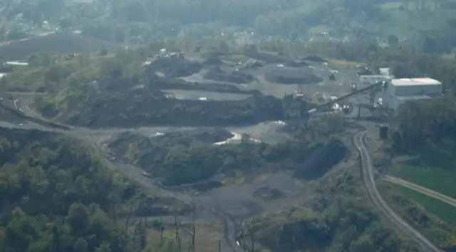 Hazy aerial of a pit and processing plant on a hillside with haul roads