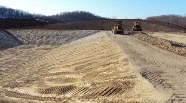 Dozers on the crest of a graded basin with tracked fill in the foreground
