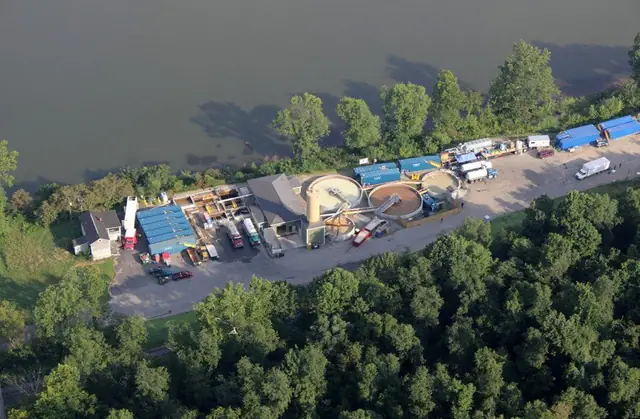 Aerial of a plant and equipment yard on a wooded riverbank