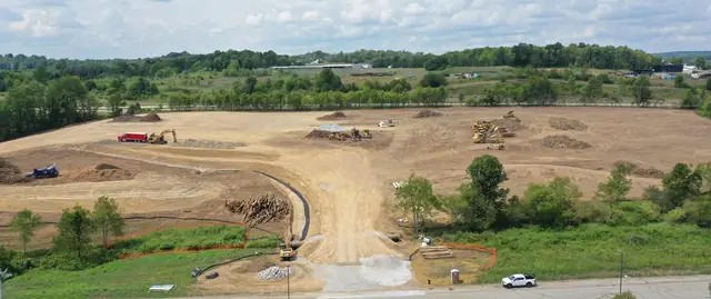Wide view of a cleared site with a haul road and equipment on the pad